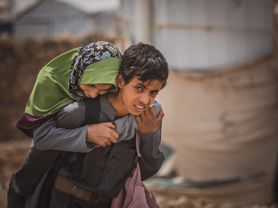 Bien qu'il soit épuisé par le travail et l'école, le jeune garçon met tout en oeuvre pour aider sa famille. Chaque jour, il porte sa sœur handicapée au dos pour l'emmener à l'école. Il est déterminé à faire en sorte qu'elle aussi reçoive l'éducation qu'elle mérite. © UNICEF/UNI530316/Alhamdani