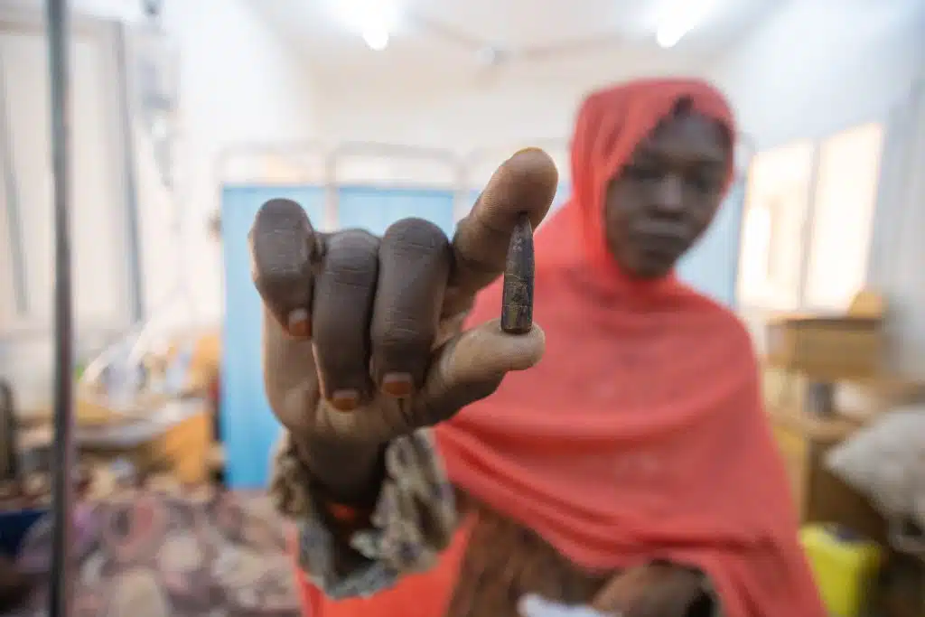 Samah tient entre ses mains la balle qui a été retirée de la tête de sa fille Fatima, âgée de 8 ans. Piégée dans la ville d'Omdurman, au Soudan, la petite fille a reçu une balle alors qu'elle prenait son petit-déjeuner. © UNICEF/UNI631159/Elfatih