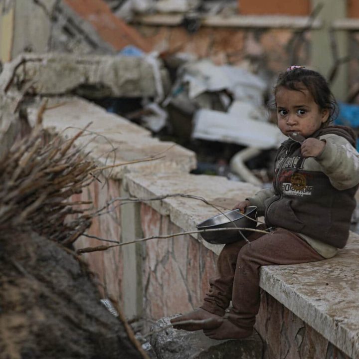 Alma, 2 ans, mange un repas sur un muret en ruine, Gaza City, Al-Rimal, mars 2025. © UNICEF/UNI767014/Nateel