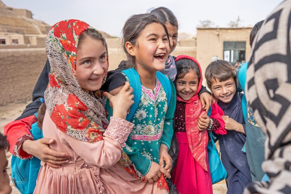 Des élèves discutent devant le centre d’éducation communautaire soutenu par l’UNICEF dans le village de Jar Qalandar, dans la province de Badghis, en Afghanistan. Photo prise en octobre 2024. © UNICEF/UNI697641/Naftalin
