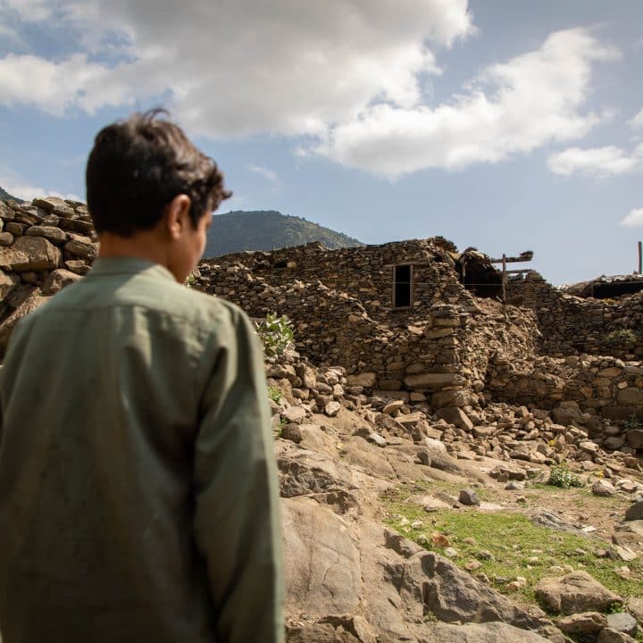 [Afghanistan Séisme 2025] Dans la province de Kundar, ce garçon se tient devant sa maison détruite par le puissant séisme de magnitude 6 qui a frappé l'est de l'Afghanistan la nuit du 31 août 2025. © UNICEF/UNI856954/Meerzad