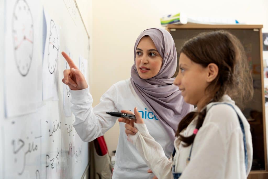 Le 31 août 2022, l'ambassadrice de bonne volonté de l'UNICEF, Muzoon Almellehan, participe à un cours de mathématiques aux côtés de Shahed, 10 ans, lors d'une visite aux enfants du centre Makani soutenu par l'UNICEF à Amman-Est, en Jordanie. © UNICEF/UN0696284/Matas