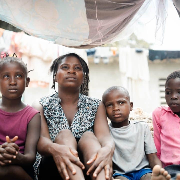 Une mère est assise entourée de ses trois enfants dans un camp de déplacés à Léogâne, juin 2024. ©UNICEF/UNI601255/Le Lijour