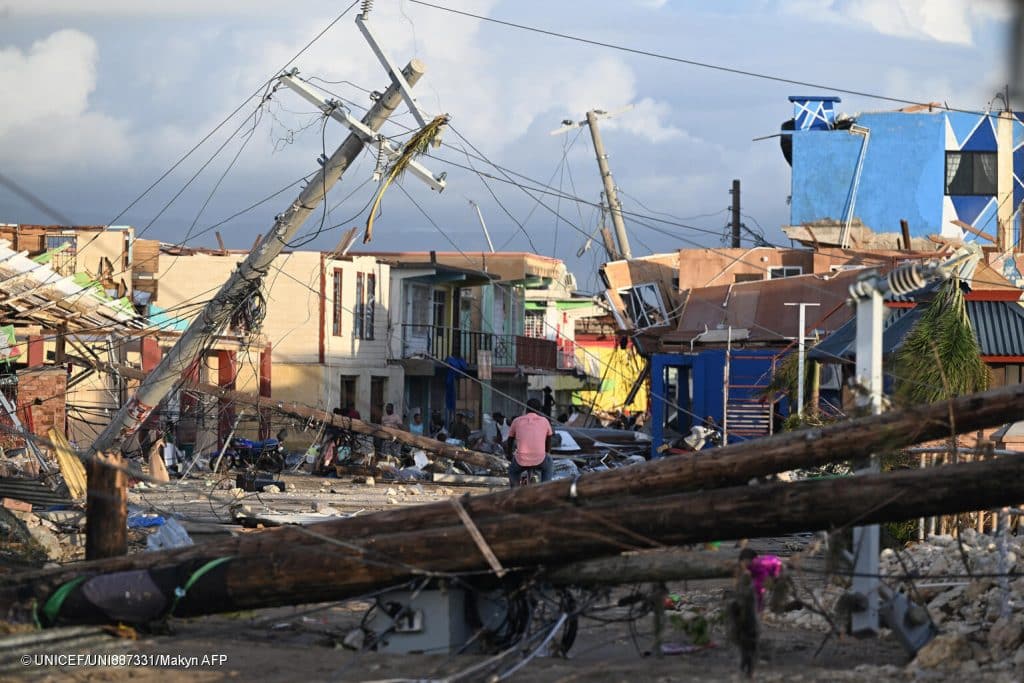 Des poteaux électriques sont tombés alors qu'un homme traverse à vélo le quartier détruit de North Street après le passage de l'ouragan Melissa, à Black River, en Jamaïque, le 29 octobre 2025. © UNICEF/UNI887331/Makyn AFP