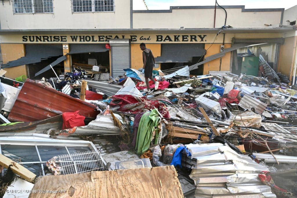 Un jeune homme marche sur les décombres laissés dans la rue après le passage de l'ouragan Melissa, à Black River, en Jamaïque, le 29 octobre 2025. © UNICEF/UNI887332/Makyn AFP