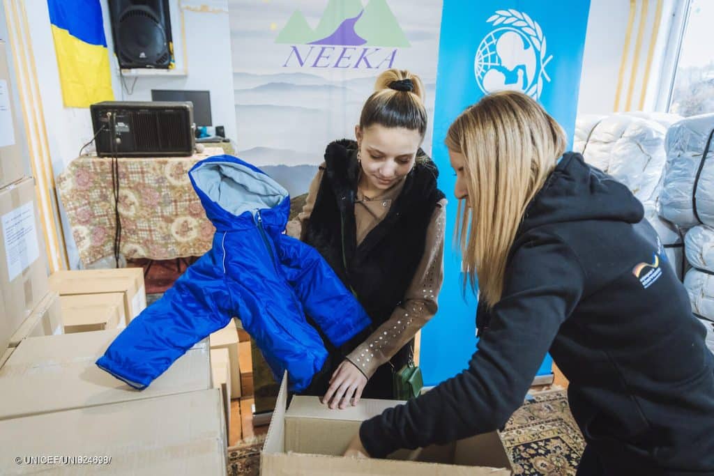 Des enfants et leurs familles reçoivent des vêtements chauds pour l'hiver lors d'une distribution soutenue par l'UNICEF à Oujgorod, en Ukraine. © UNICEF/UNI824700/