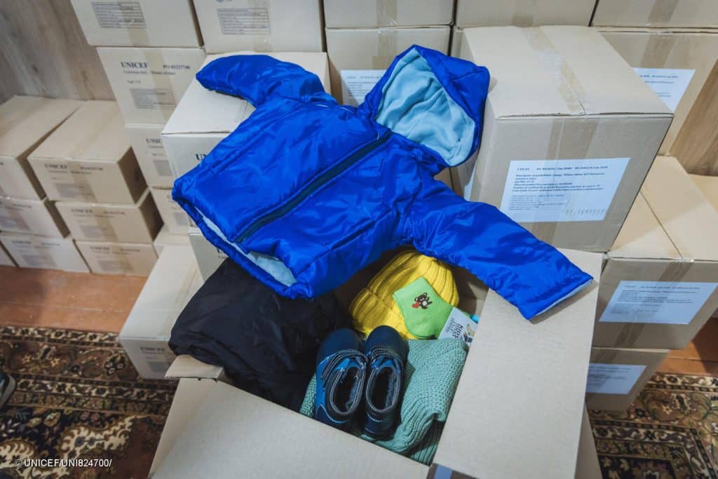 Des enfants et leurs familles reçoivent des vêtements chauds pour l'hiver lors d'une distribution soutenue par l'UNICEF à Oujgorod, en Ukraine. © UNICEF/UNI824700/