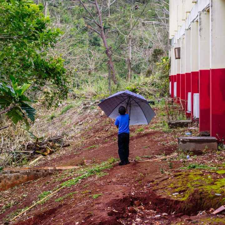 Un garçon s'abrite de la pluie alors qu'il se rend au lycée York Castle, endommagé par l'ouragan Melissa. Browns Town, Jamaïque, le 5 novembre 2025. © UNICEF/UNI895433/Pryce