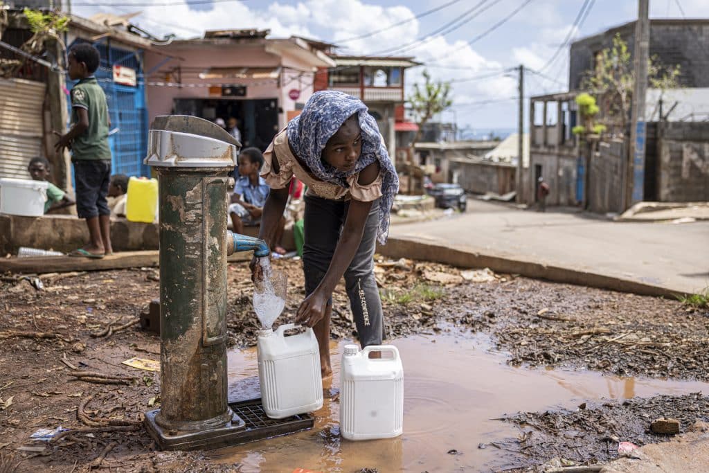 13 jours après le cyclone Chido, une fillette remplit des bidons d’eau. Les services d’accès à l’eau potable et l’électricité ne sont pas encore rétablis. Koungou, Mayotte, le 27 décembre 2024. ©Patrick Meinhardt / AF