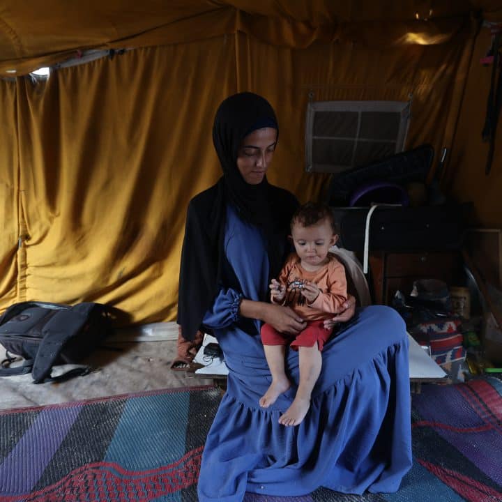 Rania tient sa fille Lareen, 1 an et demi, dans ses bras. Toutes deux ont souffert de malnutrition aiguë sévère avant d'être aidées par l'UNICEF. Al-Mawasi, bande de Gaza, octobre 2025. © UNICEF/UNI879912/El Baba