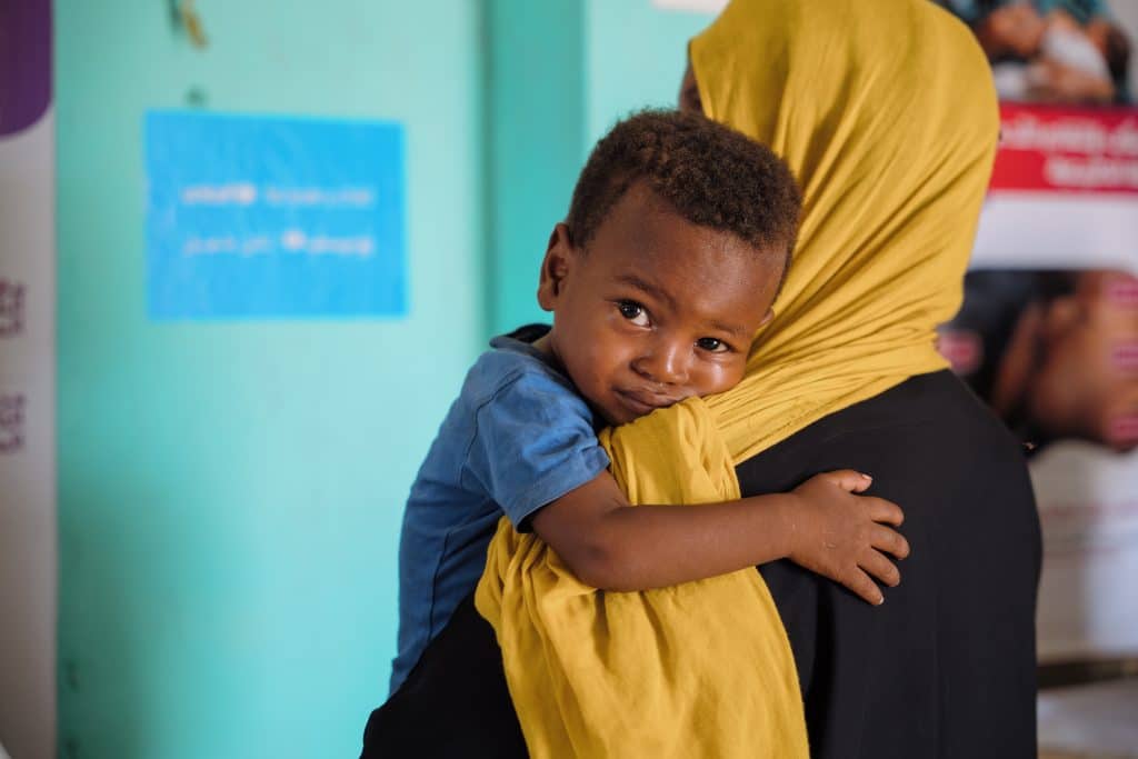 Le 8 décembre 2025, un jeune garçon attend d'être soigné dans un centre de santé soutenu par l'UNICEF sur le site de déplacés internes d'As-Senniya, à Port-Soudan.